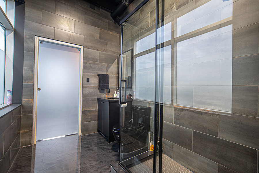 Industrial Style Bathroom with Glass Shower & Dark Tiles